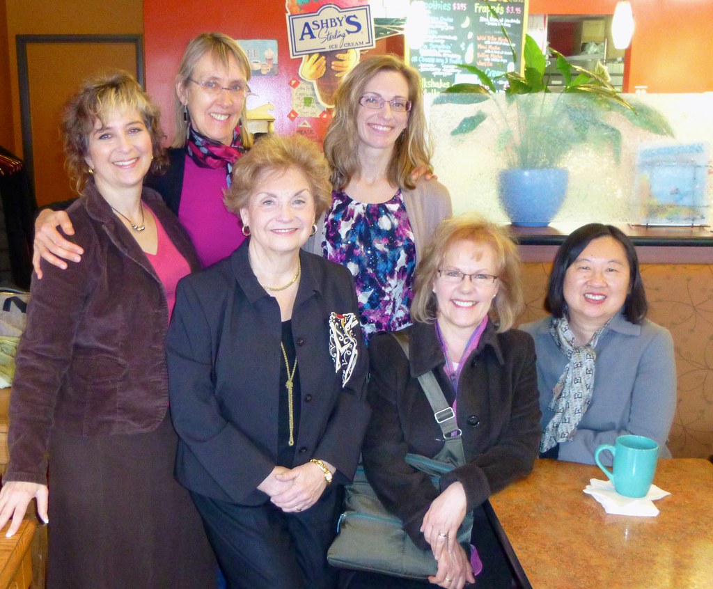 Group of smiling women posing together inside a cafe
