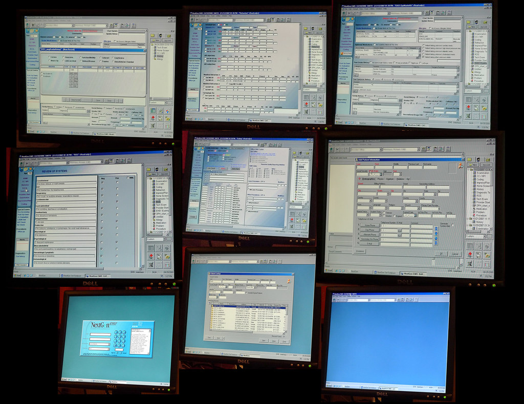 Wall of computer monitors displaying software windows and data tables